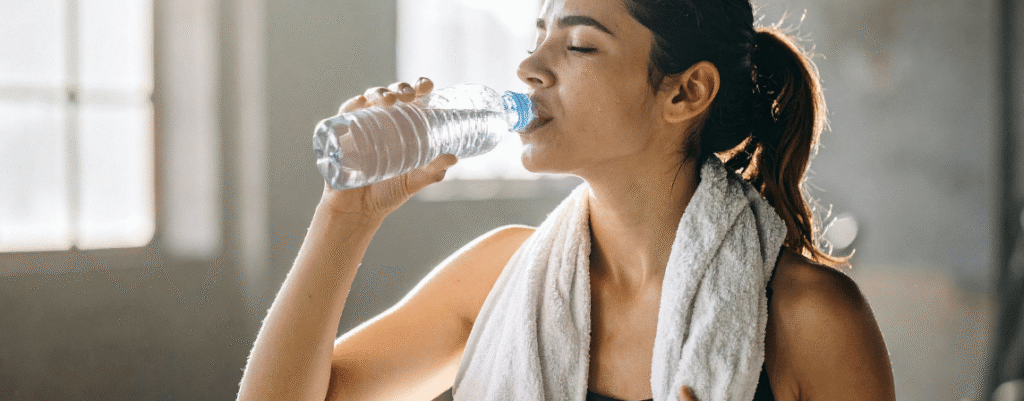 woman drinking water with towel around neck