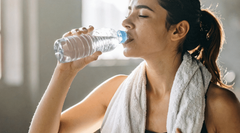 woman drinking water with towel around neck