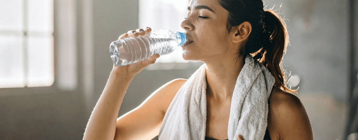 woman drinking water with towel around neck